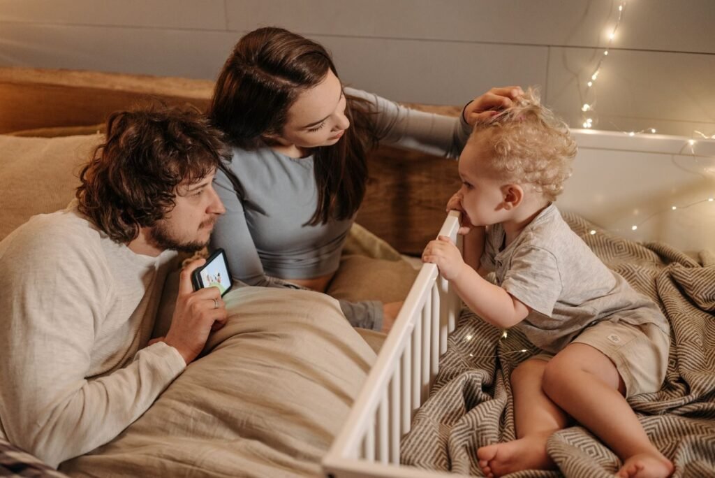 A cozy family scene depicting parents interacting lovingly with their young child in a bedroom setting.